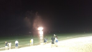 A beach scene at night with people standing by the water. - Boryeong Laon Pension (Boryeong)