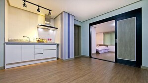 A modern kitchen with white cabinets, a built-in stove, and a wooden floor. - Boryeong Laon Pension (Boryeong)