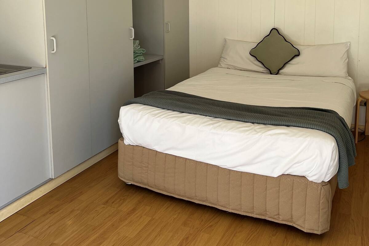 Ein Schlafzimmer mit einem Bett, einem Kleiderschrank und einem kleinen Tisch.