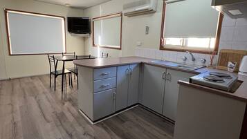 Una cocina compacta con comedor, electrodomésticos integrados y un televisor de pantalla plana.