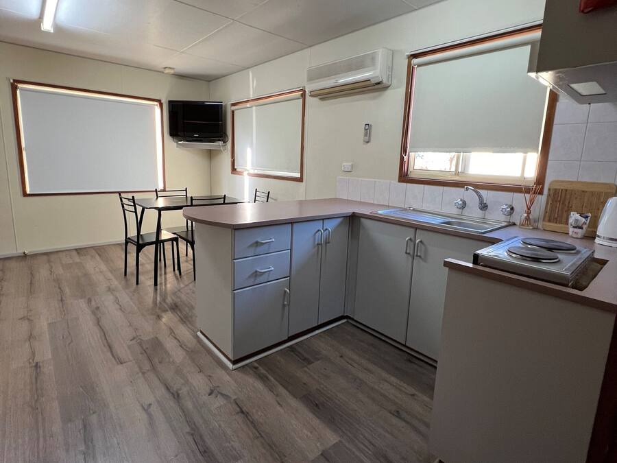 Una cocina compacta con comedor, electrodomésticos integrados y un televisor de pantalla plana.