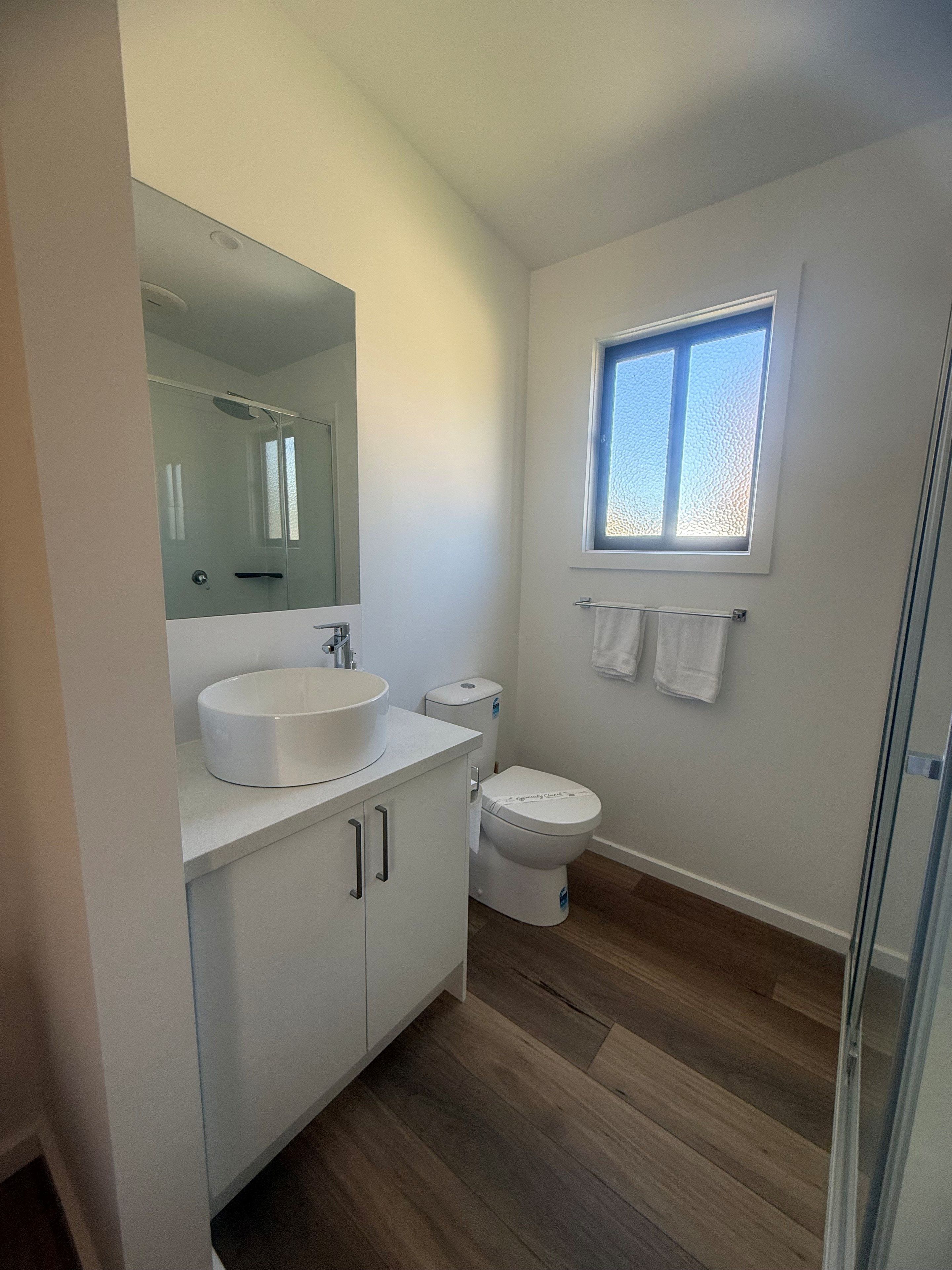 A modern bathroom with a glass shower enclosure, a white sink, and a toilet.