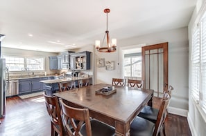 Een moderne keuken met donkere kastjes, een centraal eiland en een eethoek met een houten tafel en stoelen.