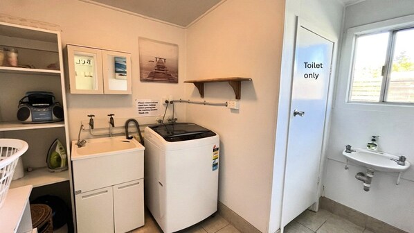 A compact bathroom with a washing machine, a sink, and a toilet.