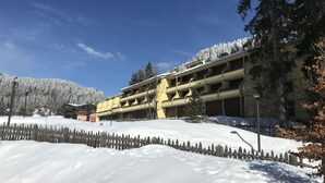 Un hotel a più piani con un tetto innevato e un recinto in legno di fronte.