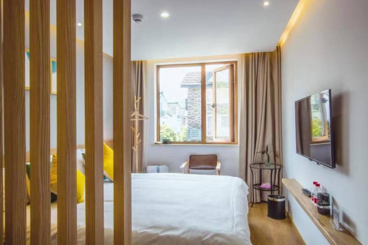 Hotelkamer met een bed, een stoel, een televisie en een raam met uitzicht op gebouwen.