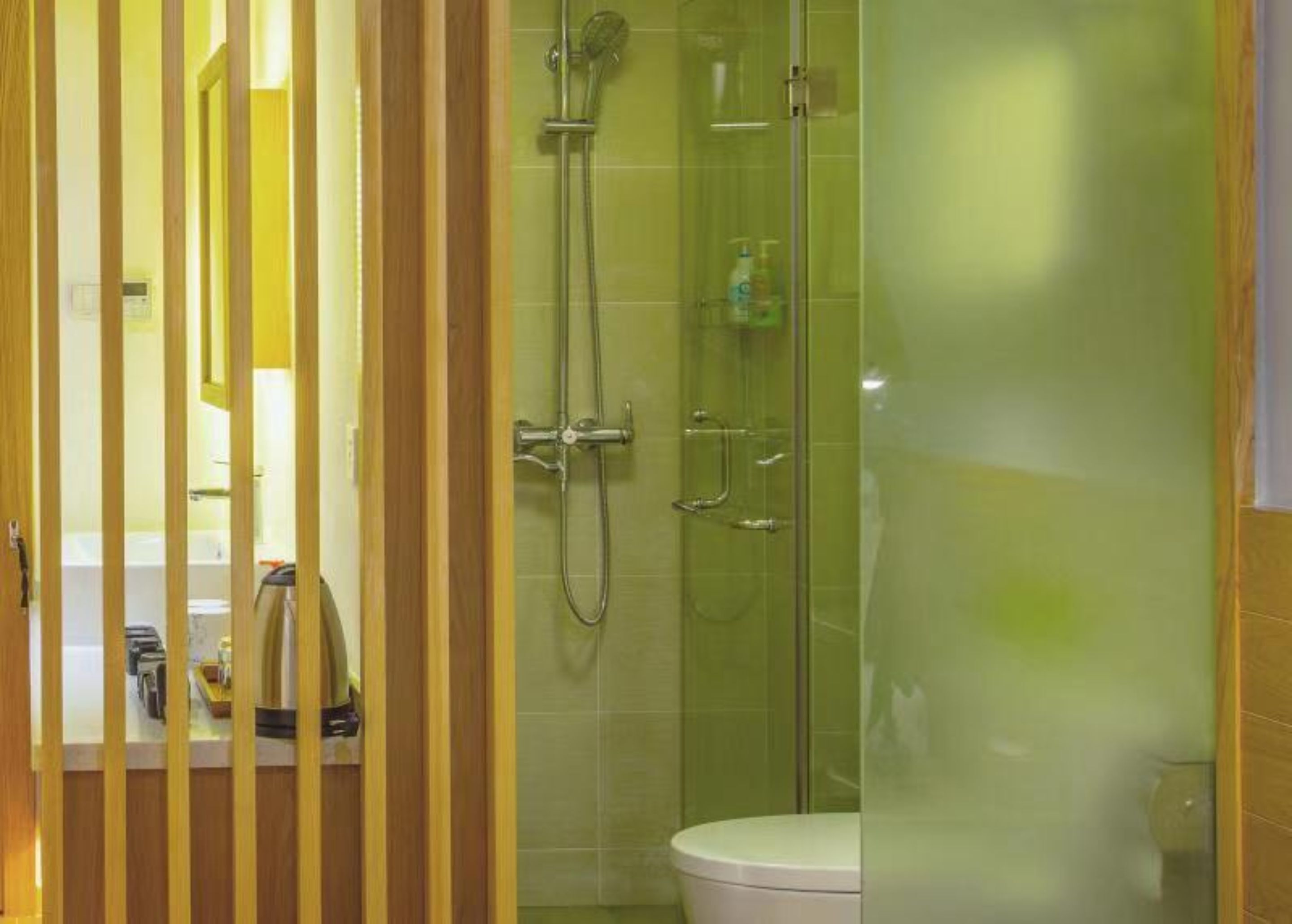 A modern bathroom with a glass-enclosed shower, a toilet, and a sink with toiletries.