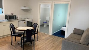 Un espacio habitable compacto con kitchenette, comedor y dormitorio.