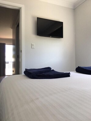 A hotel room with a bed, a flat-screen TV mounted on the wall, and a neatly folded towel on the bed. - Terminus Hotel Coonamble (Coonamble)