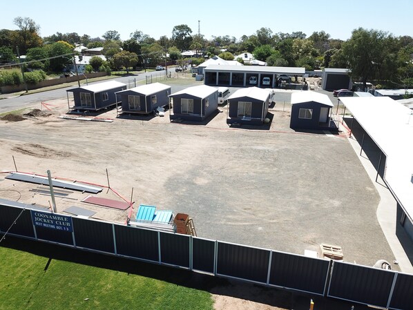 A large parking area with several small, dark-colored structures, possibly mobile units or temporary accommodations, arranged in rows.