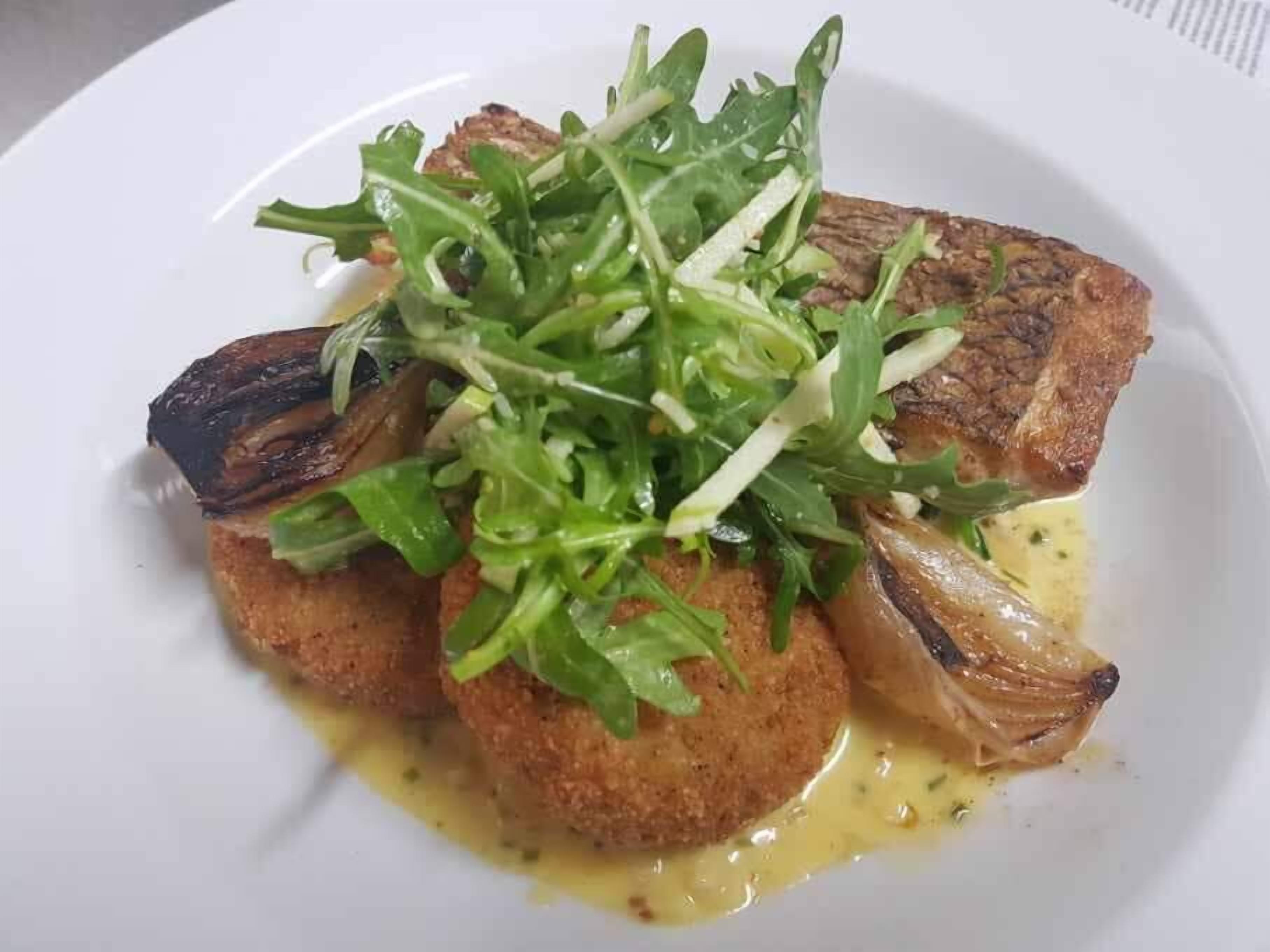 Um prato com carne grelhada, uma salada verde e um molho cremoso.