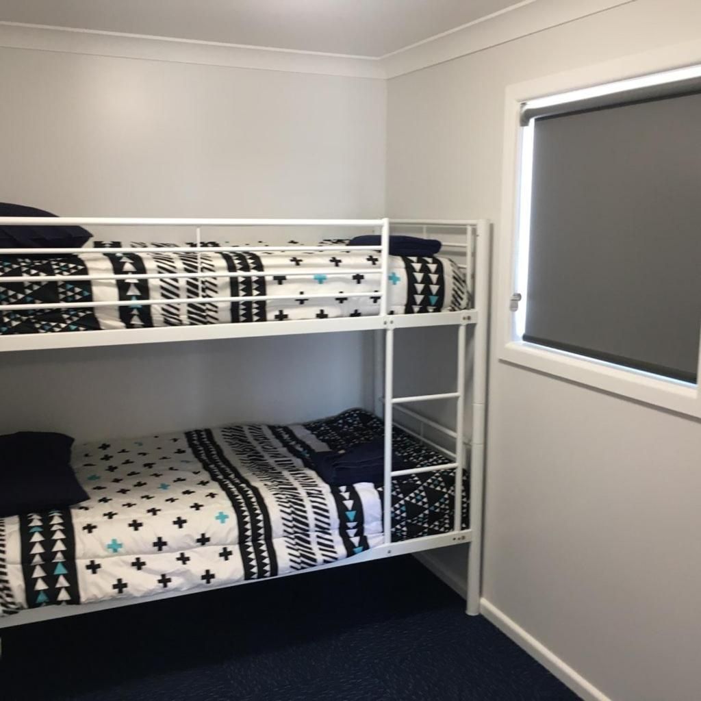 A bunk bed with patterned bedding in a room with a window.