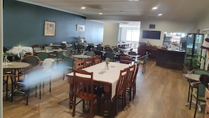 Un restaurante espacioso con numerosas mesas y sillas, una barra y vistas a la calle.