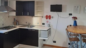 A modern kitchen with a gas stove, sink, and a dining area with a table and chairs.