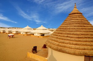 A desert resort with thatched-roof tents and a large central building.