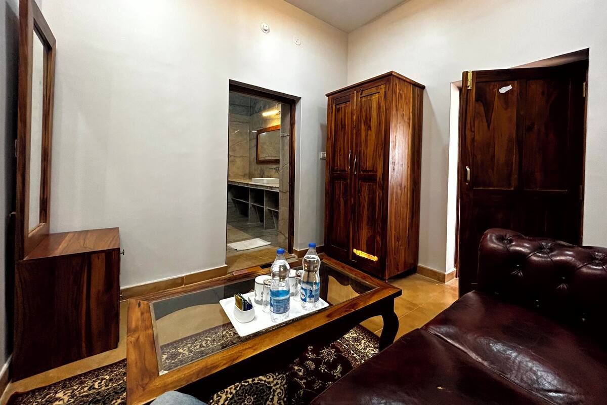 Een woonkamer met een glazen salontafel, een leren bank, een houten garderobe en een spiegel.