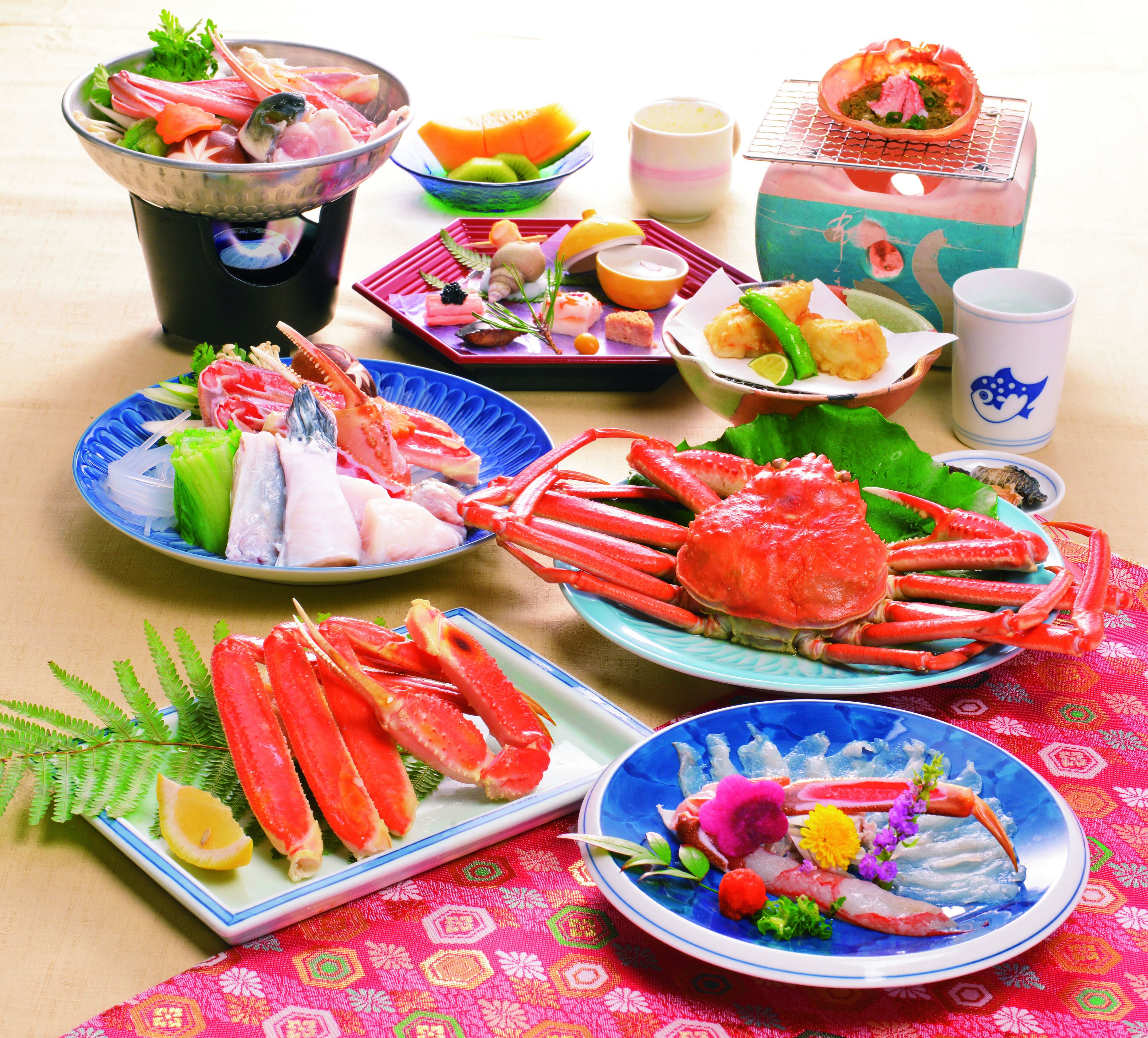 A table with various seafood dishes, including crab legs and sashimi, arranged on plates.