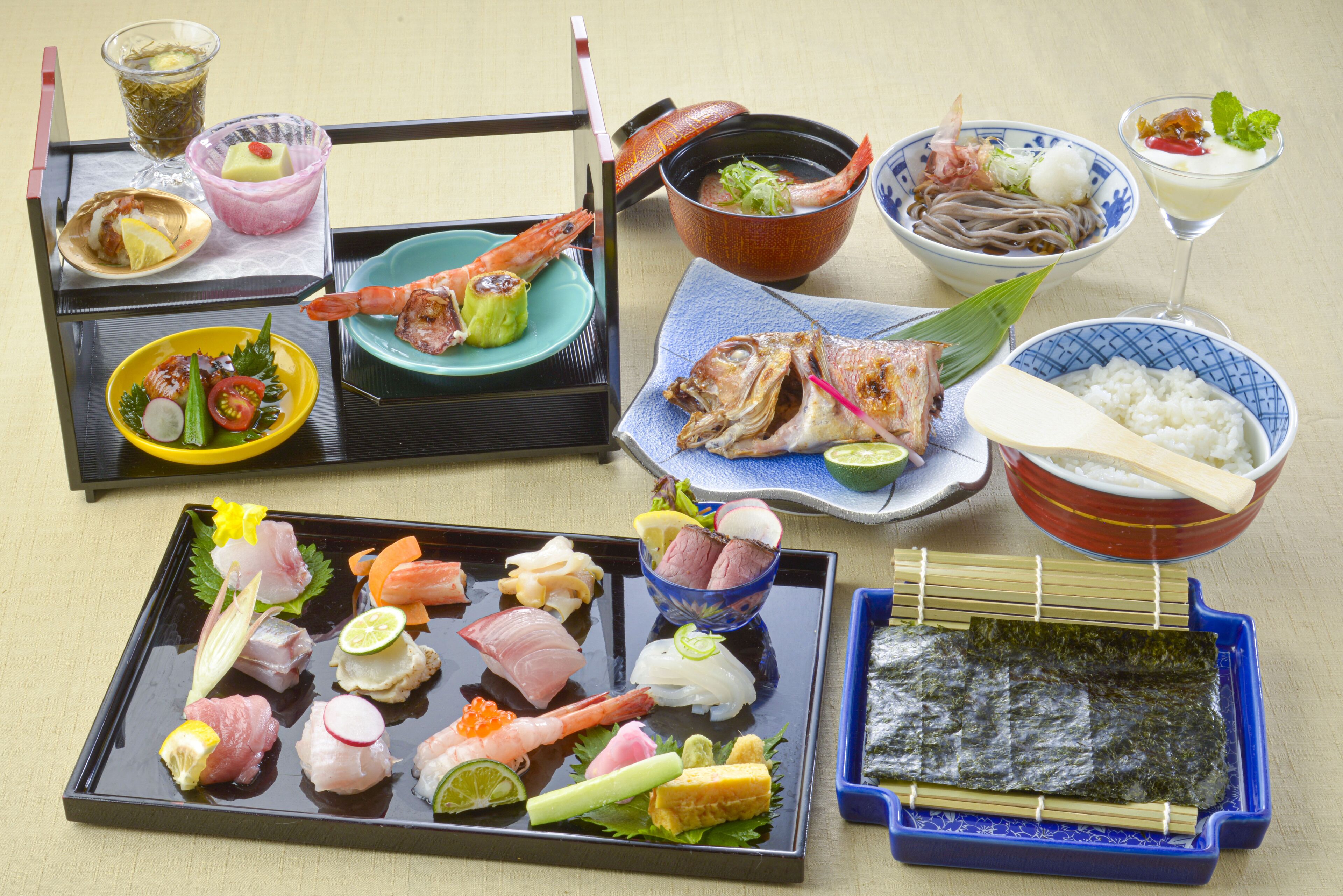 A variety of Japanese dishes including sashimi, rice, and vegetables, arranged on a table.