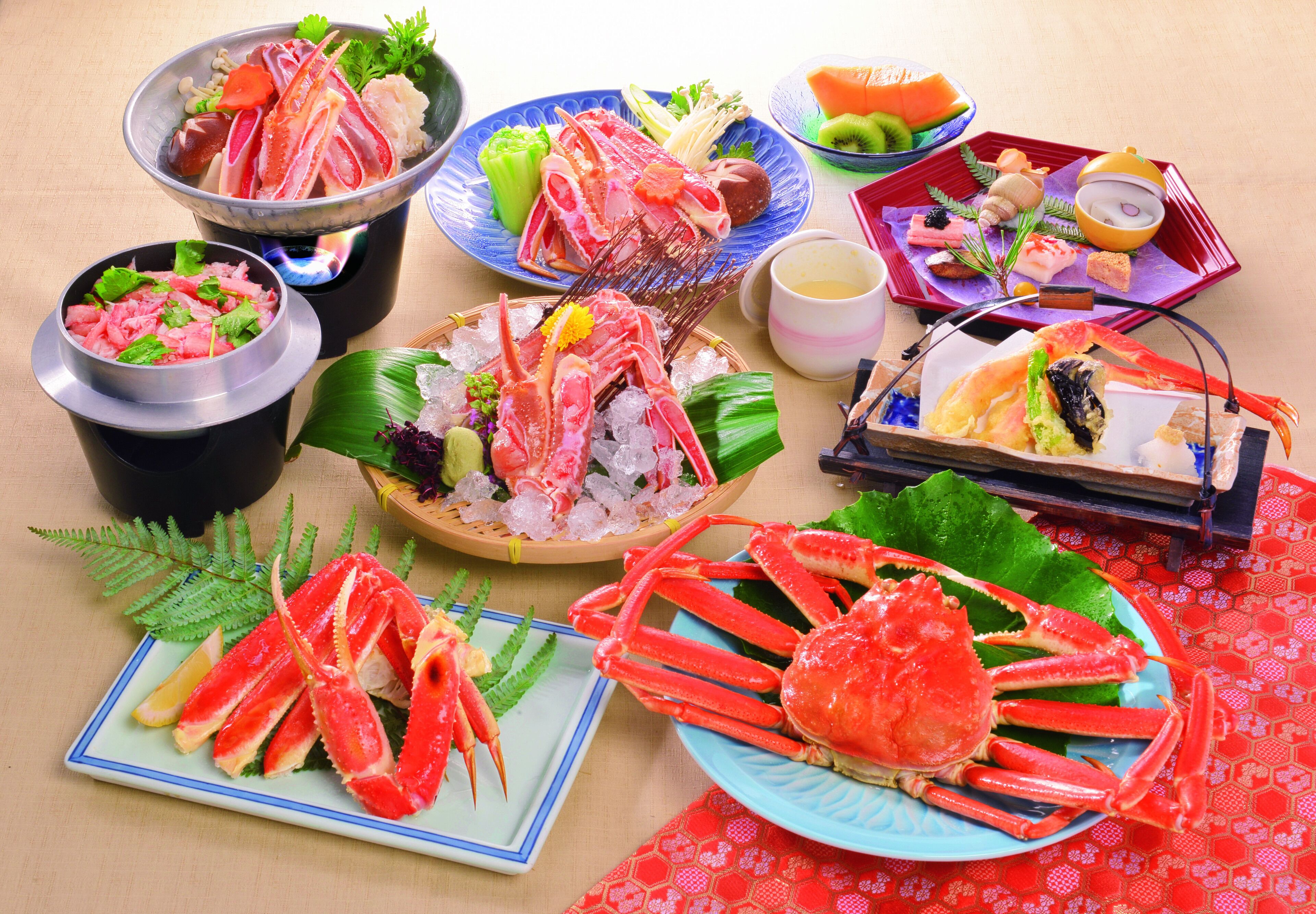 Diverse visgerechten, waaronder krabbenpoten en sashimi, gepresenteerd op een tafel met een rode tafelkleed.