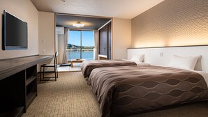 Una habitación de hotel con cama, escritorio, televisor y vistas al exterior.
