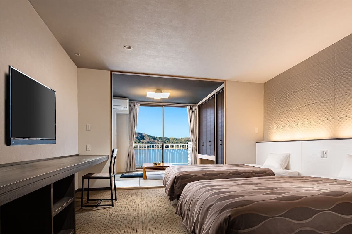 Une chambre d’hôtel équipée d’une télévision, de deux lits, d’un bureau et d’un balcon avec vue.