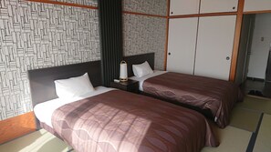 A hotel room with two beds, a nightstand with a lamp, and a wardrobe. - The Gran Resort Akou (Ako)