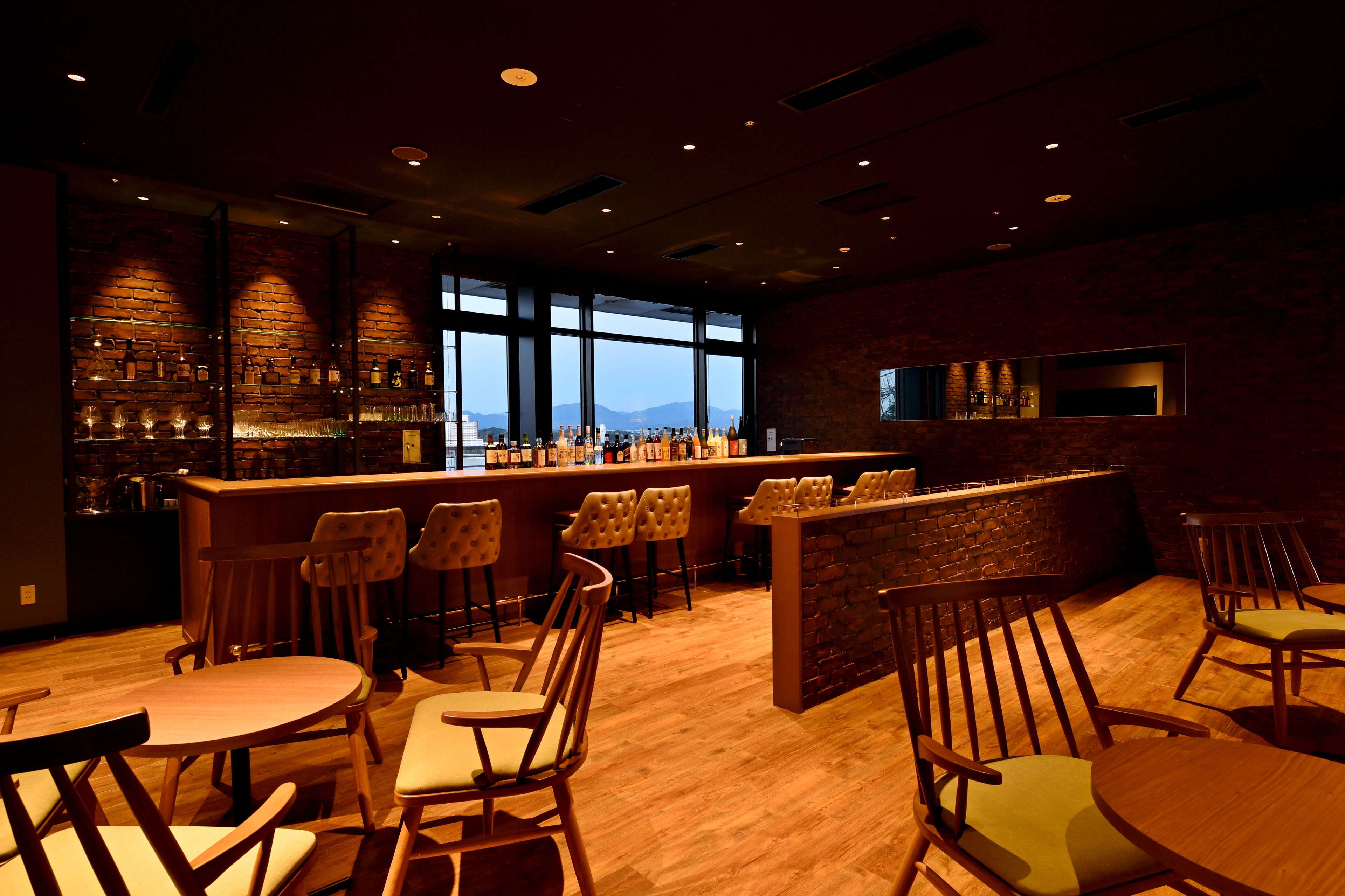A bar area with wooden furniture, a brick wall, and a large window offering a view.