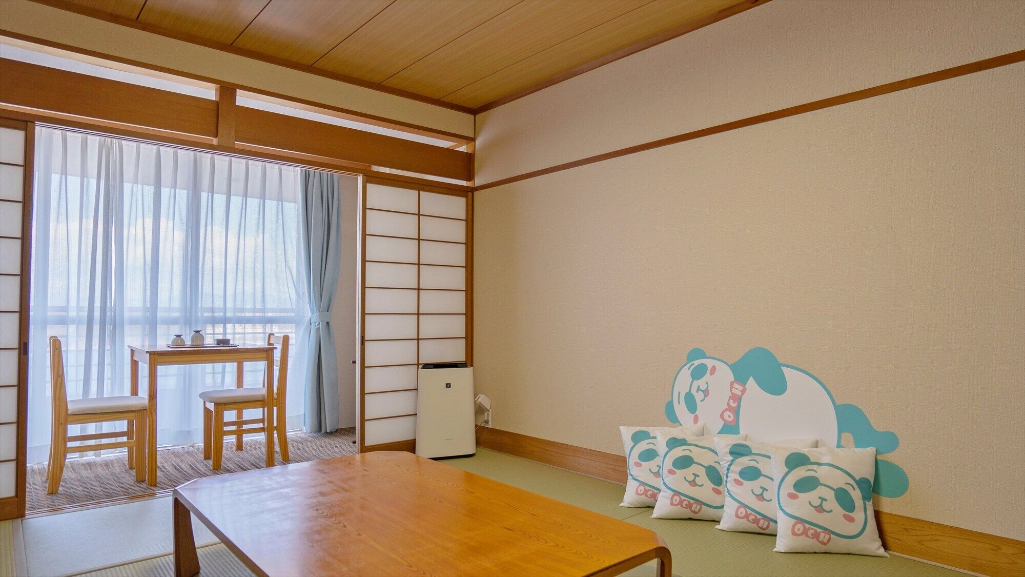 Perinteinen japanilainen huone, jossa on tatamimatto, matala pöytä, sohva ja shoji-liukuovet.