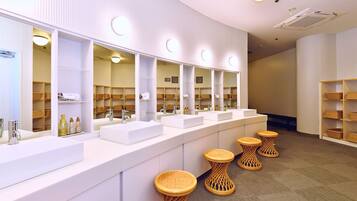 A modern bathroom with multiple sinks, mirrors, and wicker stools.