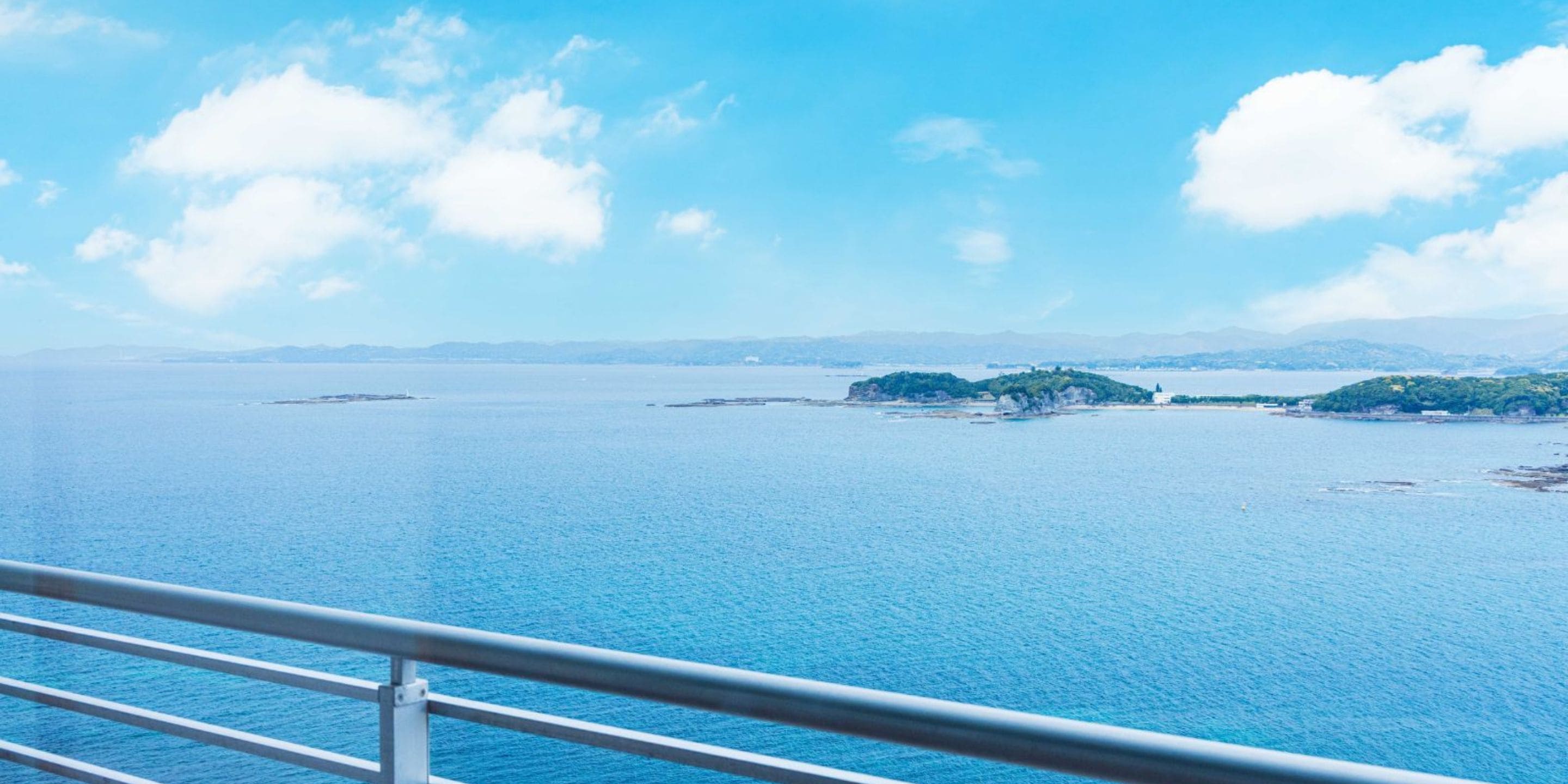 A coastal view with a clear sky, calm sea, and distant landforms.
