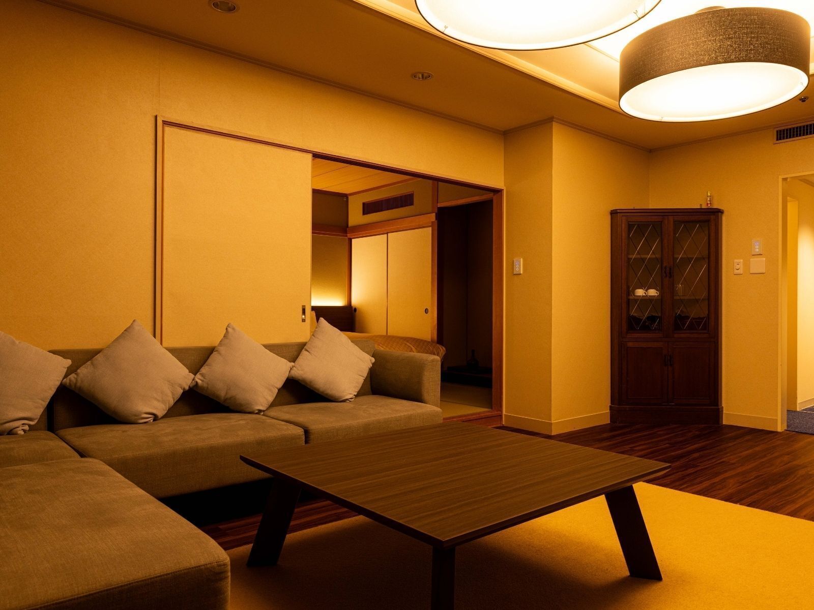 A room with a sofa, a wooden coffee table, and a cabinet with glass doors.