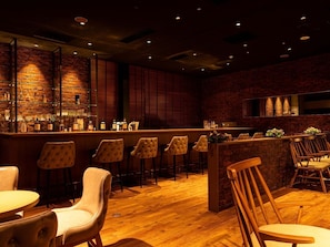 Un espace bar avec un plancher en bois, des tabourets de bar et un mur en briques.