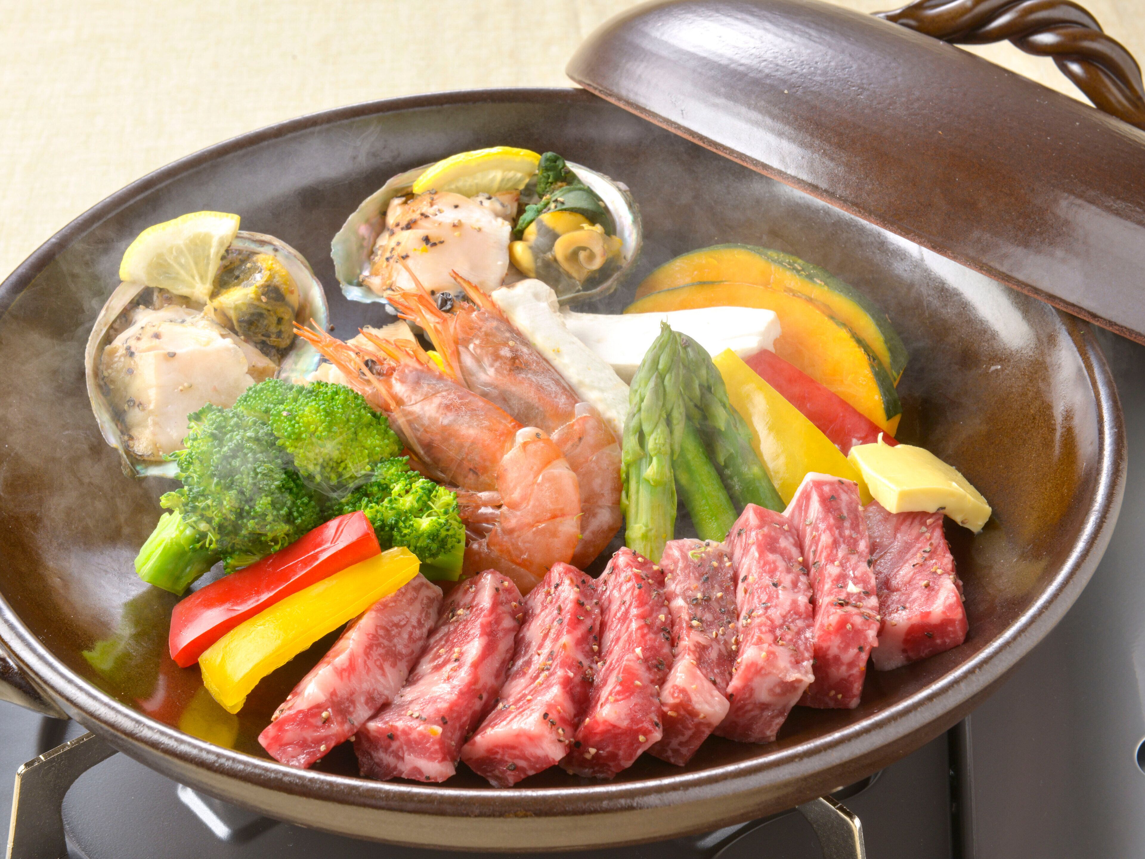 A hot pot with various ingredients including shrimp, meat, vegetables, and mushrooms.