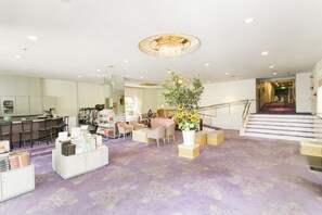 A spacious hotel lobby with a purple carpet, a chandelier, a staircase, and a reception desk. - The Grand Resort Arima (Kobe)