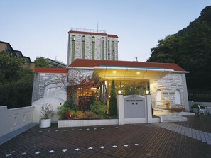 A hotel entrance with a stone facade, a red roof, and a sign that reads "The Gran Resort." - The Grand Resort Arima (Kobe)