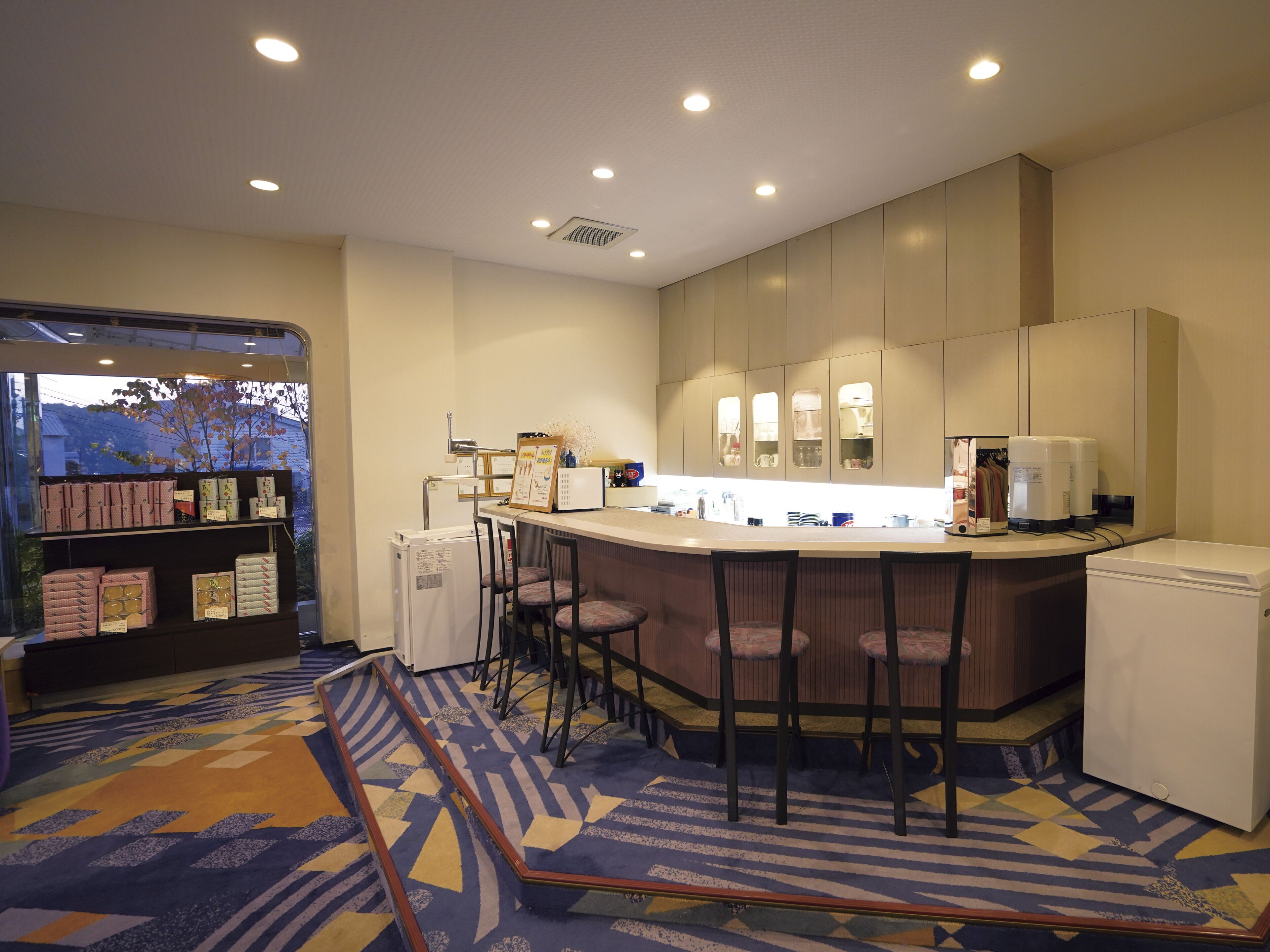 Una cocina de hotel con barra, un refrigerador y una exhibición de productos envasados.
