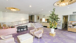 En rummelig lobby med trappe, siddeområde og en receptionsdisk.