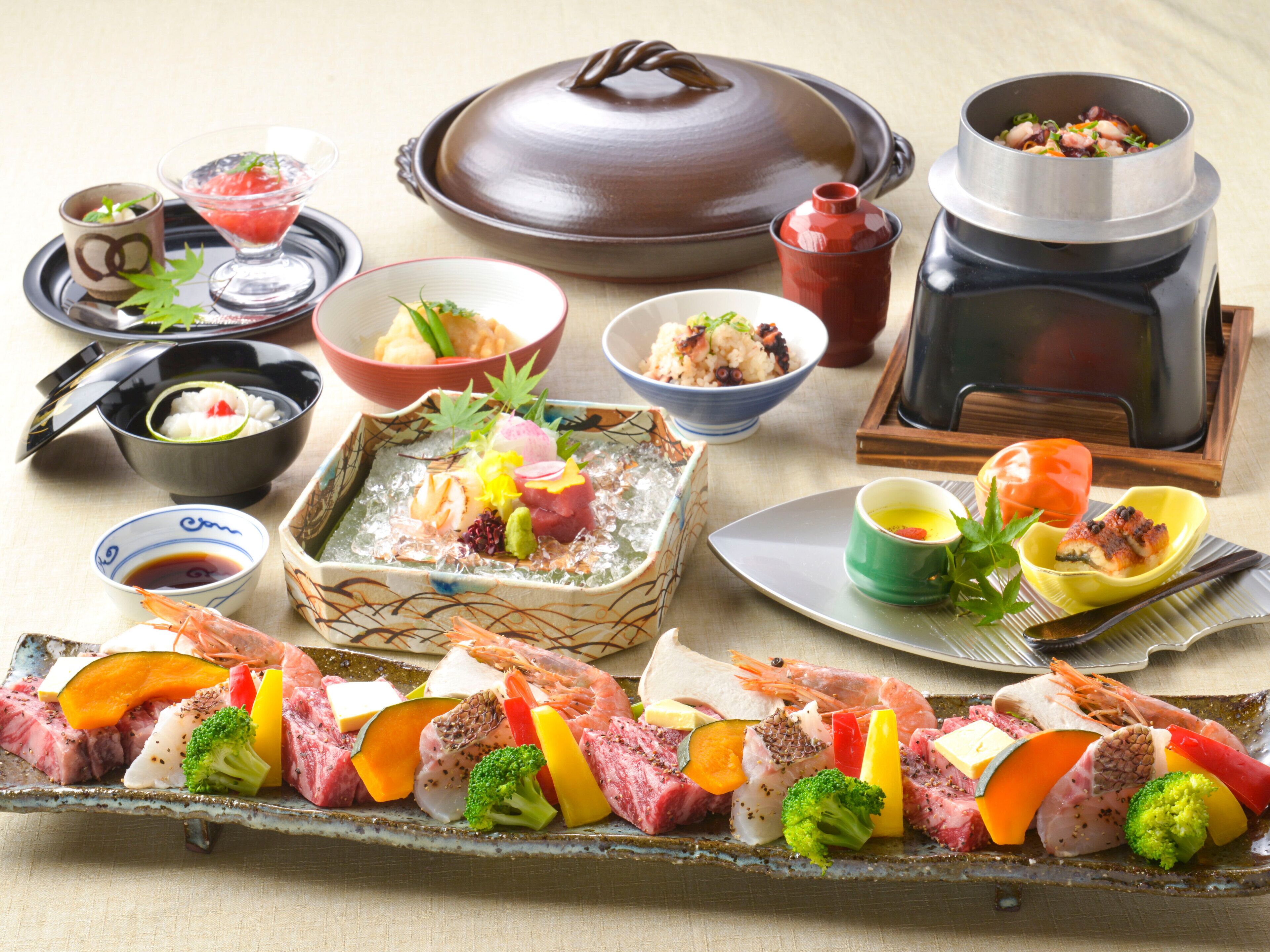 Verschiedene japanische Gerichte, darunter Sashimi, Gemüse und ein Fondue.