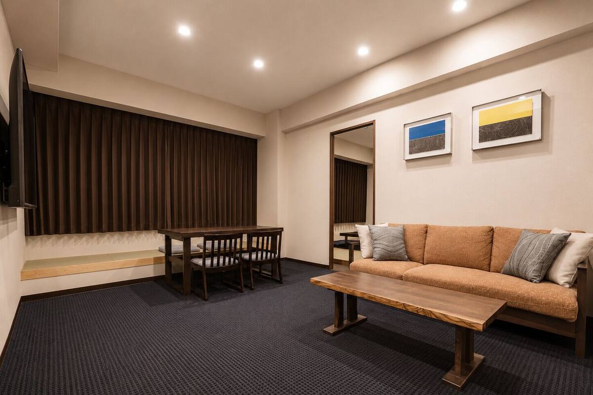 A modern room with a sofa, a wooden table, a TV, and a large window with curtains.