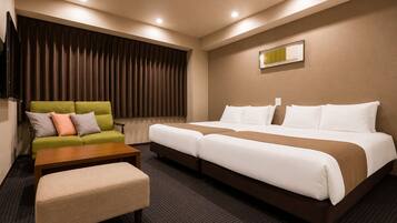 A hotel room with a green sofa, a wooden coffee table, a bench, and a double bed with white bedding.