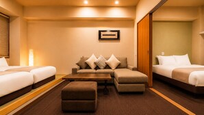 A hotel room with a sofa, two single beds, a wooden coffee table, and a carpeted floor. - Randor Residential Hotel Kyoto Suites (Kyoto)