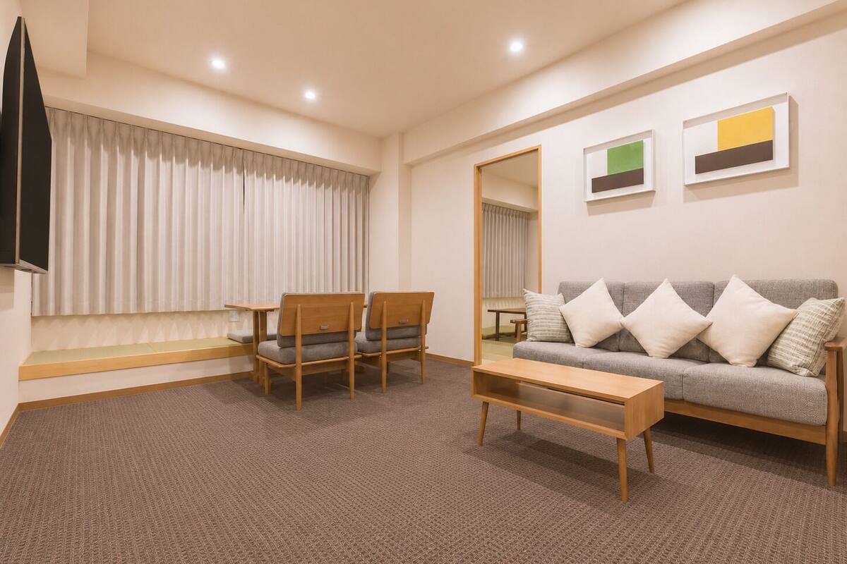 A modern living room with a sofa, chairs, a coffee table, a TV, and artwork on the wall.