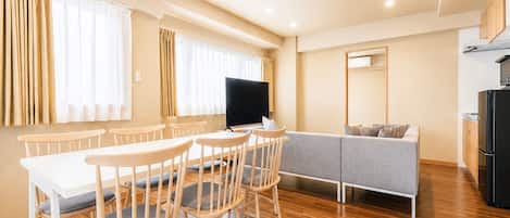 Una sala de estar moderna con comedor, un sofá y un televisor.