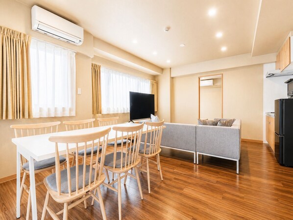 Una sala de estar moderna con comedor, un sofá y un televisor.