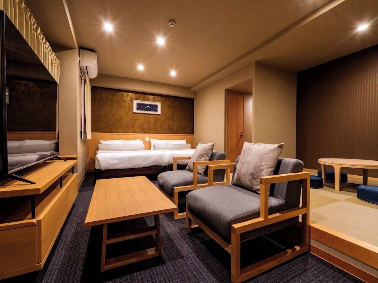 Una habitación de hotel con una cama, dos sofás, un televisor, una mesa y una mesita.