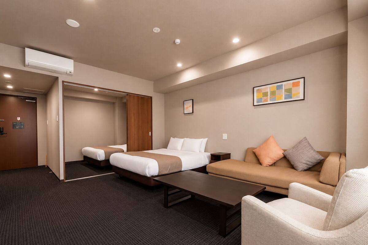 A hotel room with two beds, a sofa, a coffee table, and a painting on the wall.