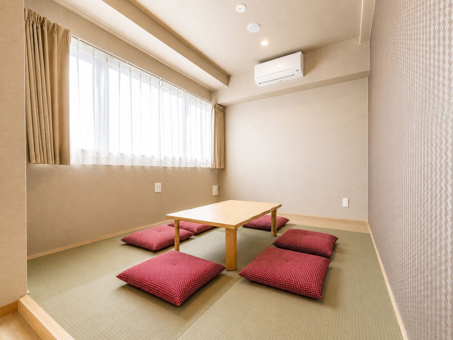 A room with tatami flooring, a wooden table, and red cushions.