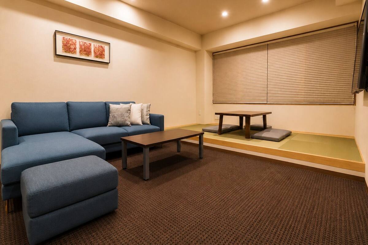 A living room with a sofa, ottoman, coffee table, and a low table with cushions.