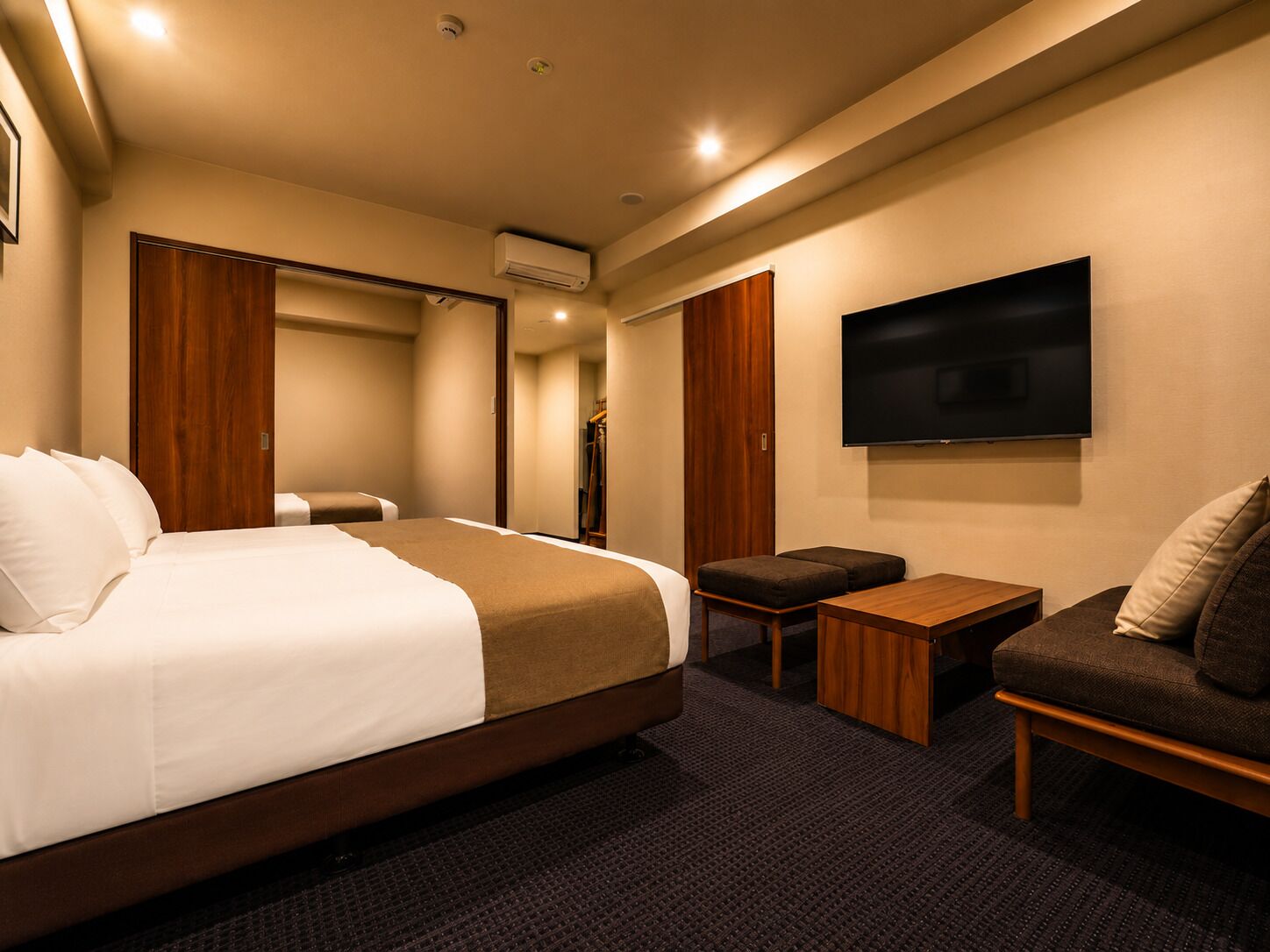Una habitación de hotel con una cama, televisión, sofá y una mesita.