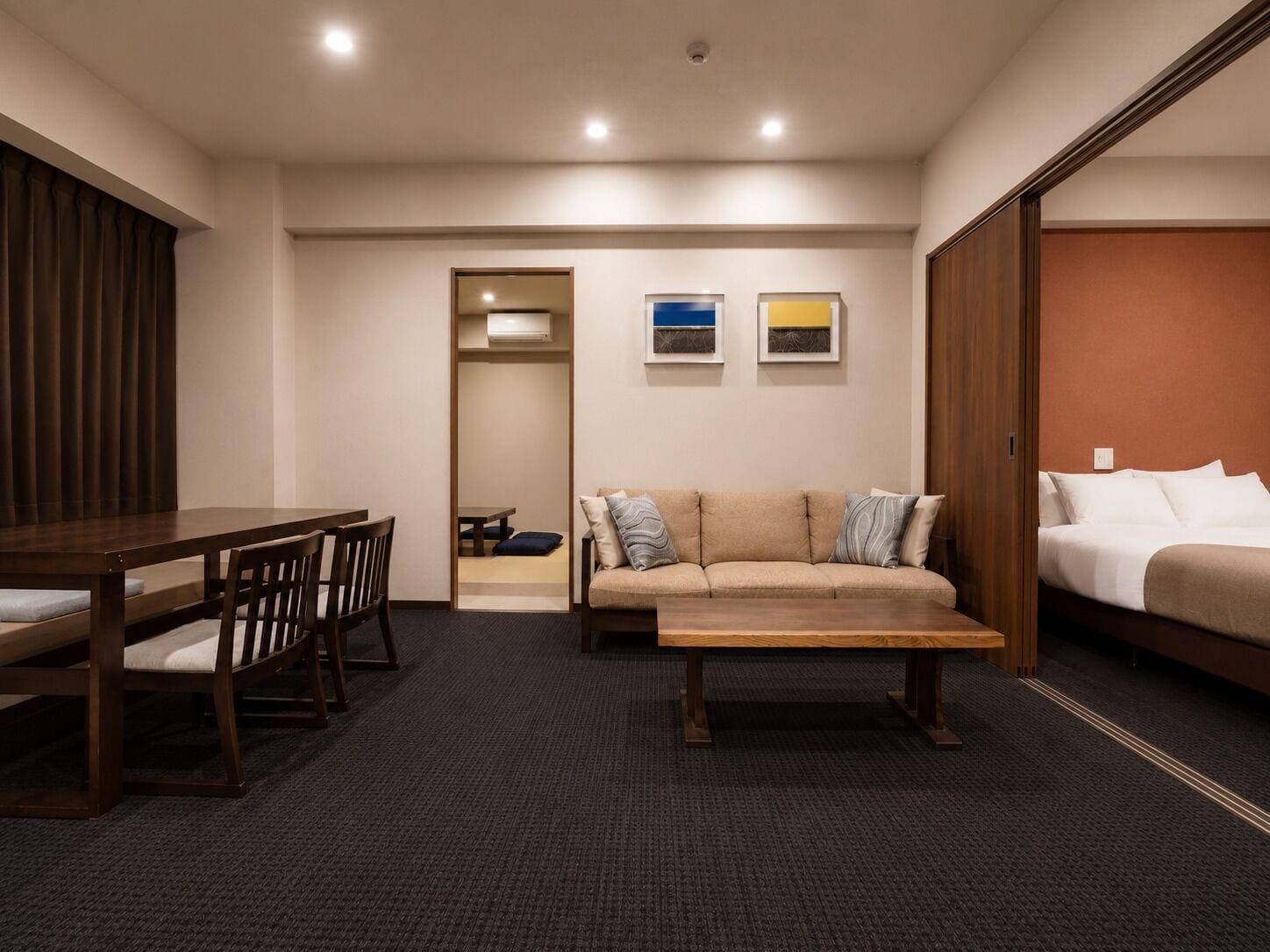 Habitación de hotel con cama, sofá, mesa de comedor y una pequeña cocina.